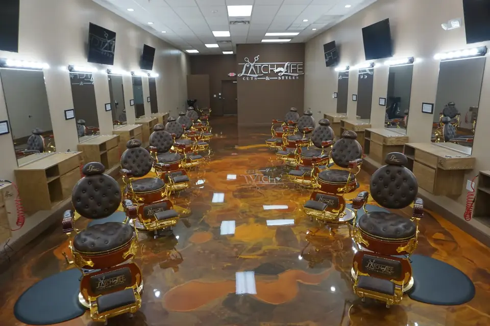 Rows of black and gold barber chairs on an amber floor inside a Latch Life shop